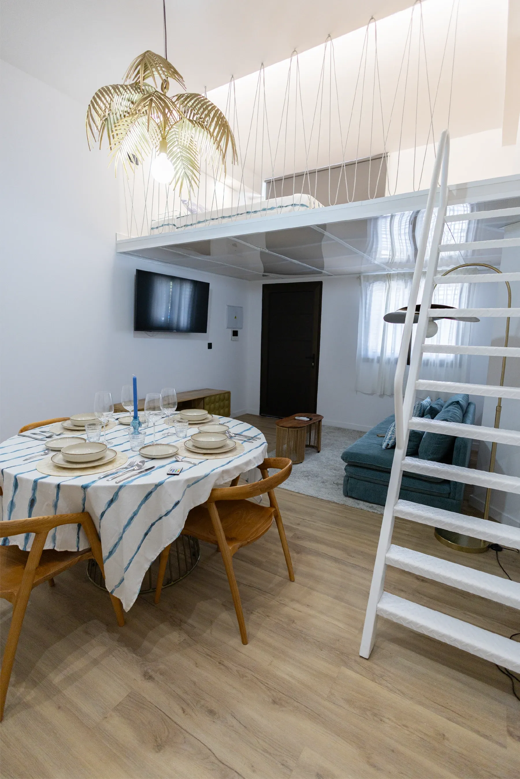Comedor de una de las viviendas vacacionales de Lemusa Stays con candelabro dorado y escalera blanca