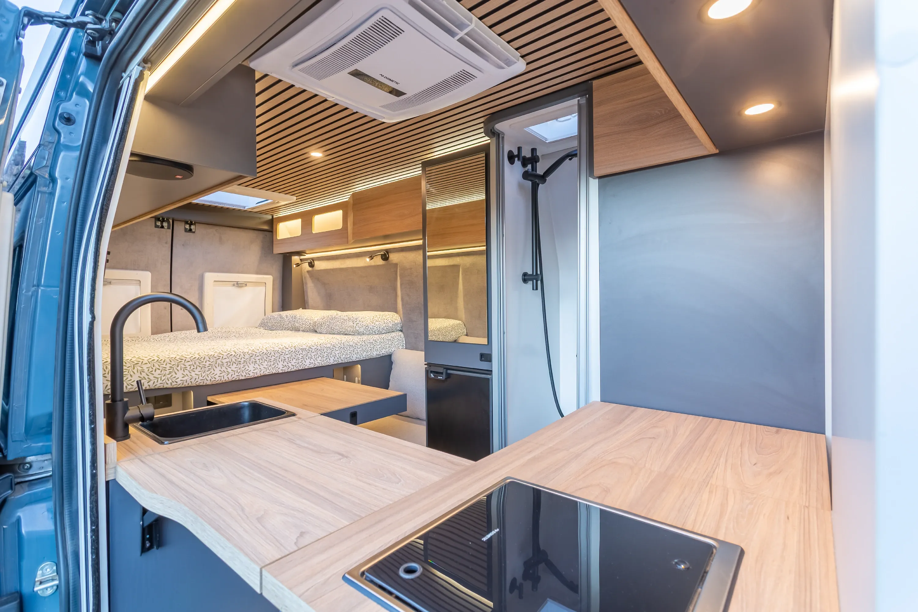 Interior de la camper Fiat Ducato de Lemusa Stays, con cocina, cama transversal y todo equipado